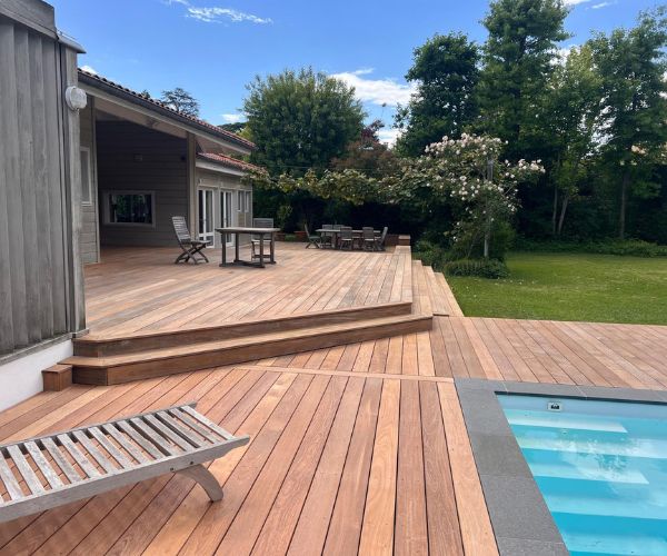 Terrasse en bois IPE autour d’une piscine dans un jardin aménagé – Atout Rénov